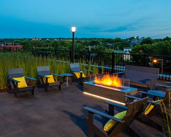 Outdoor lounging area with fireplace and comfortable seating.